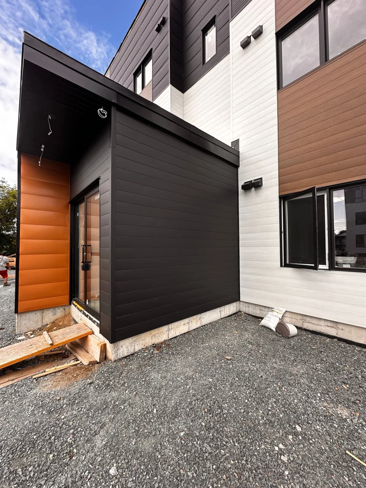 Side entrance in black steel, next to wood-tone steel