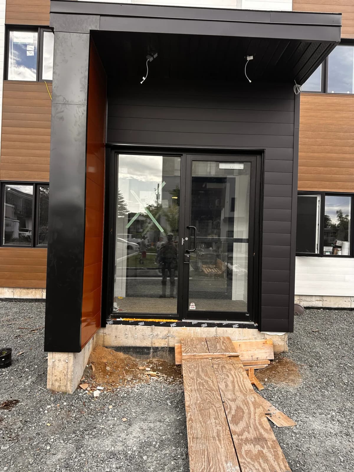Main entrance clad in black steel and wood-tone steel